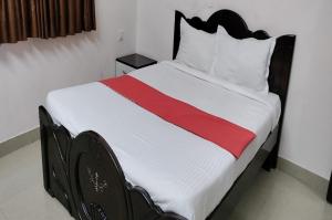 a bedroom with a bed with a red stripe on it at STAYMAKER Anjaneya Comforts in Shimoga