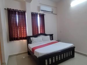 1 dormitorio con 1 cama con cortinas rojas en STAYMAKER Anjaneya Comforts, en Shimoga