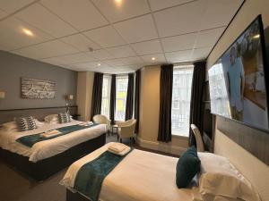 a hotel room with two beds and a flat screen tv at The Port Hotel in Portrush