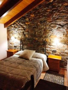 a bedroom with a bed and a stone wall at Casa los Ancares in Vega de Espinareda