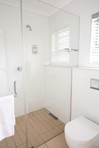 a white bathroom with a toilet and a shower at Perfek Stay Guesthouse in Secunda