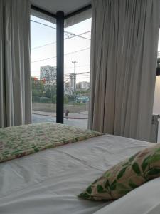 1 dormitorio con cama y ventana grande en Alquiler temporario con pileta y Sum en Córdoba