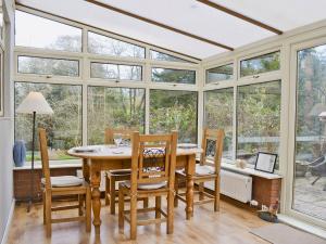 a dining room with a table and chairs and windows at Damson Lodge in Chetton