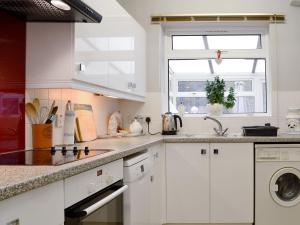 a kitchen with white cabinets and a window at Damson Lodge in Chetton