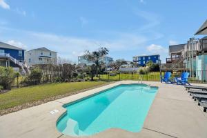 - une piscine avec des chaises bleues à côté d'une cour dans l'établissement Oak Island Escape with Saltwater Pool, Walk to Beach, à Île au chêne
