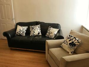 czarna skórzana kanapa i krzesło w salonie w obiekcie Leigh Accommodation w mieście Leigh
