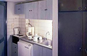 a small kitchen with a sink and a stove at Blue Sky Hotel Apartments in Tolo