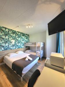 a bedroom with two beds and a flat screen tv at Cit'Hôtel La Résidence in Villebois