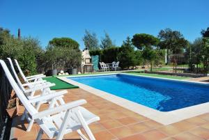 a swimming pool with white chairs next to at Club Villamar - Andes in Lloret de Mar