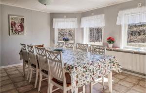 a dining room with a table and chairs and windows at Nice Home In Lngekrr With Kitchen in Klövedal