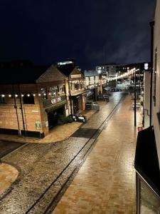 uma rua vazia à noite com edifícios e luzes em The Flat on Humber Street em Hull