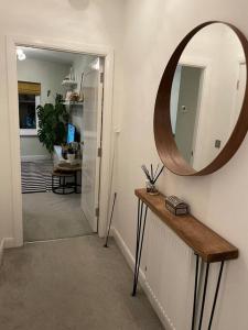 un pasillo con un espejo en la pared y una mesa en The Flat on Humber Street en Hull