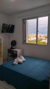 a bedroom with two towels on a bed with a window at Apto do Thiago e da Chori in Porto Alegre