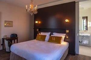 a bedroom with a large bed and a chandelier at Hôtel Villa Walbaum in Vallon-Pont-dʼArc