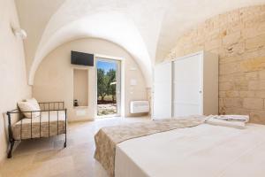 1 dormitorio con 1 cama grande y 1 silla en Masseria Macchia, en Ceglie Messapica