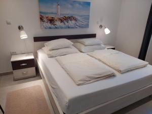 una camera da letto con un letto con lenzuola e cuscini bianchi di Gavza Dream View apartment a Cres