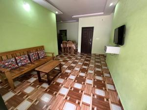 Camera con divano, TV e pavimento in legno. di ISHRA SERVICE APARTMENTS a Dharmastala