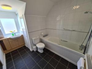 a bathroom with a tub and a toilet and a sink at Large Modern Victorian Apartment in Ventnor