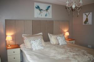 een slaapkamer met een bed met kussens en 2 lampen bij School House Cottage B&B and tea garden in Hawkshead