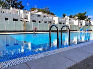 a swimming pool with blue water in front of a building at Apartment Virginia in Playa de las Americas