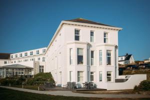 a white building with tables and chairs in front of it at Polurrian on the Lizard in Mullion