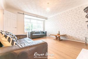 a living room with a couch and a table at Rowan Serviced Accommodation in Lowton