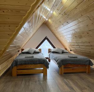2 bedden in een zolderkamer met houten plafonds bij Domek w Chmurach II in Kicznia