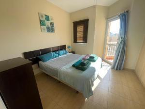 Un dormitorio con una cama con almohadas azules y una ventana. en Mi casa su casa, en Caleta de Fuste