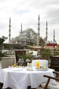 a table with food and drinks on a balcony with a mosque at Hippodrome Hotel in Istanbul