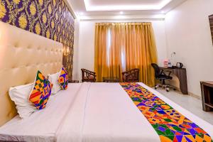 a bedroom with a large white bed with colorful pillows at FabHotel Swess Grand in Agra