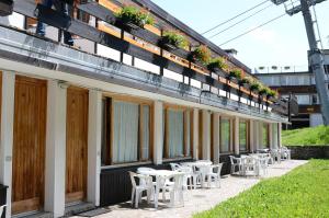 une rangée de tables et de chaises sur le côté d'un bâtiment dans l'établissement Residence Abete, à Marilleva