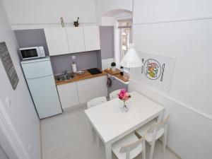 a white kitchen with a white table and chairs at Downtown apartment Tango in Zadar