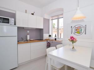 a kitchen with white cabinets and a table with a vase of flowers at Downtown apartment Tango in Zadar