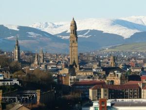 a city with a clock tower and snow covered mountains at Mackie House in Port Glasgow