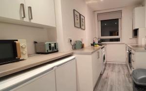 a kitchen with white cabinets and a microwave at Mackie House in Port Glasgow