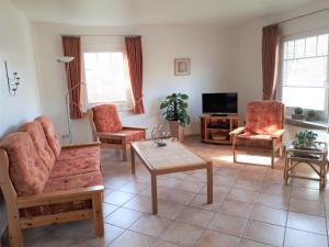 a living room with a couch and chairs and a tv at Ferienhaus Hopp in Fehmarn