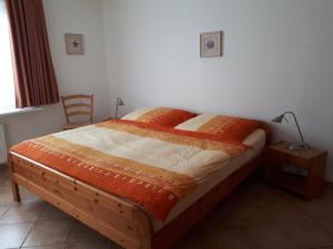 1 dormitorio con 1 cama con manta naranja y lámpara en Ferienhaus Hopp, en Fehmarn