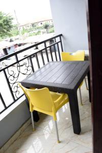 a black table and yellow chairs on a balcony at The Agore Hotels and Suites Ltd in Awoyaya