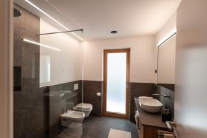 Un baño con lavabo, inodoro y espejo. en Hofer Hof Hirzer, en Lagundo