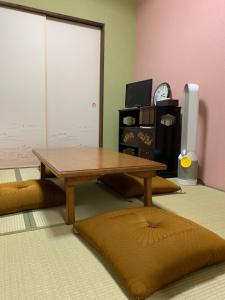 翠云間 庭院式京町屋 京都四条西院 في كيوتو: غرفة معيشة مع طاولة ووسائد خشبية