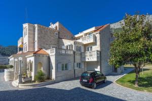 une voiture garée devant une grande maison dans l'établissement Apartments Anna, à Omiš