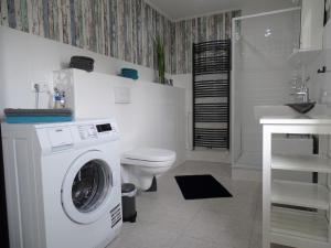 a white bathroom with a washing machine and a sink at Scheitz 3 in Dahme