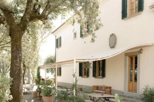 a white house with a table and a tree at Villa de' Ricci Rignana di Sveva Rocco di Torrepadula in Greve in Chianti