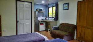 a bedroom with a bed and a chair and a door at Granja Agua Azul.A/C WiFi,2 Camas, Rio, jardines. in Fortuna