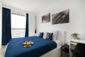 Un dormitorio con una cama azul con una bandeja de comida. en Easy Rent- Metropolitan 75 Hala Globus, 24h Check-in, Zana, en Lublin