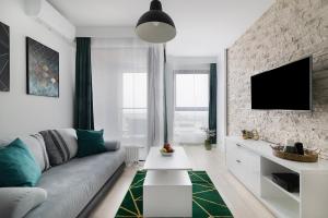 a living room with a couch and a tv on a brick wall at Easy Rent Apartments - Metropolitan 75 in Lublin