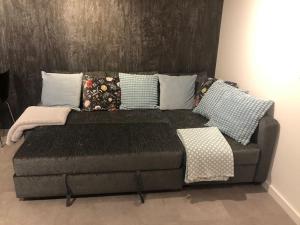 un sofá con almohadas en una habitación en Brand new studio outhouse Putney SW15 en Londres