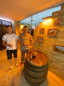 Dois homens numa sala com um barril grande. em GUEST HOUSE OCEAN FORCE em Batumi