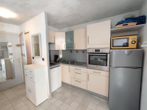 kuchnia z białymi szafkami i lodówką w obiekcie AQUAPLAGE Joli appartement RDC piscine 1 ère ligne mer Richelieu Cap d'Agde w Cap d'Agde +5 zdjęć