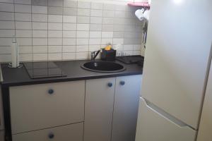 a kitchen with a sink and a white tiled wall at Brukshotellet Öland - kursgård och vandrarhem in Degerhamn